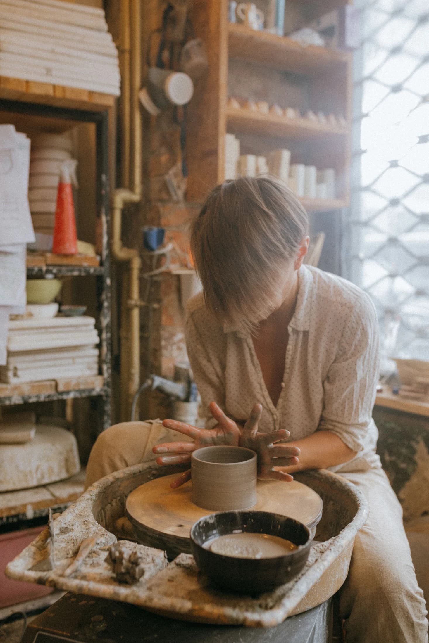 A potter shaping a bowl on the wheel